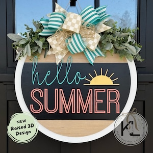 May include: A round wooden door hanger with a black chalkboard surface. The chalkboard has the text "hello summer" in turquoise and pink lettering with a yellow sun graphic. The door hanger is decorated with a green and white striped bow and greenery.