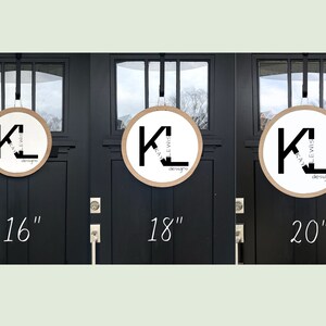 K&ouml;nnte beinhalten: Drei runde Holzschilder mit wei&szlig;er Mitte und schwarzem Text KL KAY LEWIS DESIGNS in den Gr&ouml;&szlig;en 16, 18 und 20 Zoll. Jedes Schild h&auml;ngt an einem schwarzen Riemen an einer schwarzen T&uuml;r und zeigt deutlich das Markenlogo der Firma.