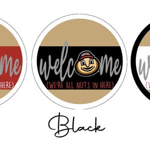 Puede incluir: Tres letreros circulares con fondos beige y una banda horizontal central en rojo, negro o blanco. Cada letrero presenta la palabra welcome en letra cursiva gris, un personaje de nuez de dibujos animados y el texto (WE'RE ALL NUTS IN HERE) en letras peque&ntilde;as.