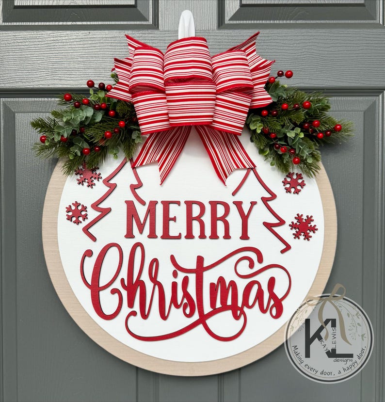 May include: A round wooden door sign with a white center and light wood border. It features red text reading MERRY CHRISTMAS, red snowflake cutouts, and two red outline pine trees. A large red and white striped bow sits atop with greenery.