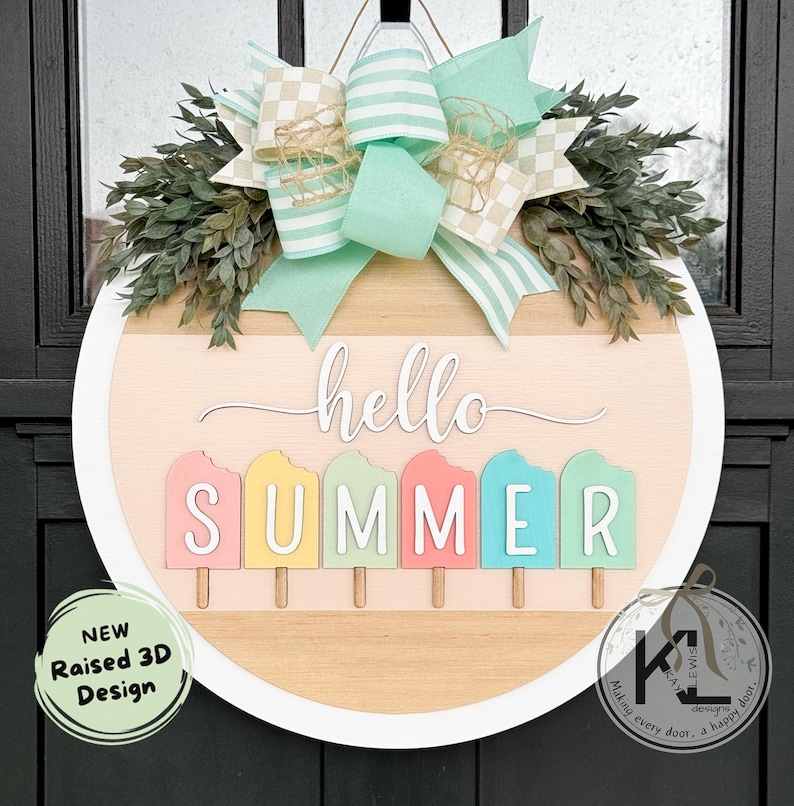 Pu&ograve; includere: Un appendiporta rotondo in legno con un bordo bianco. Il centro dell'appendiporta presenta uno sfondo in legno chiaro con il testo "hello summer" in bianco. Il testo "summer" &egrave; composto da cinque forme di ghiaccioli di diversi colori. L'appendiporta &egrave; decorato con un fiocco a scacchi verde e bianco e foglie verdi.