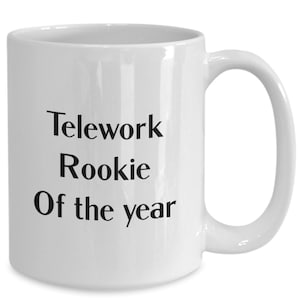 May include: White ceramic mug with a curved handle. The mug features the text "Telework Rookie Of the year" in black, centered on the front. A simple, everyday coffee mug.