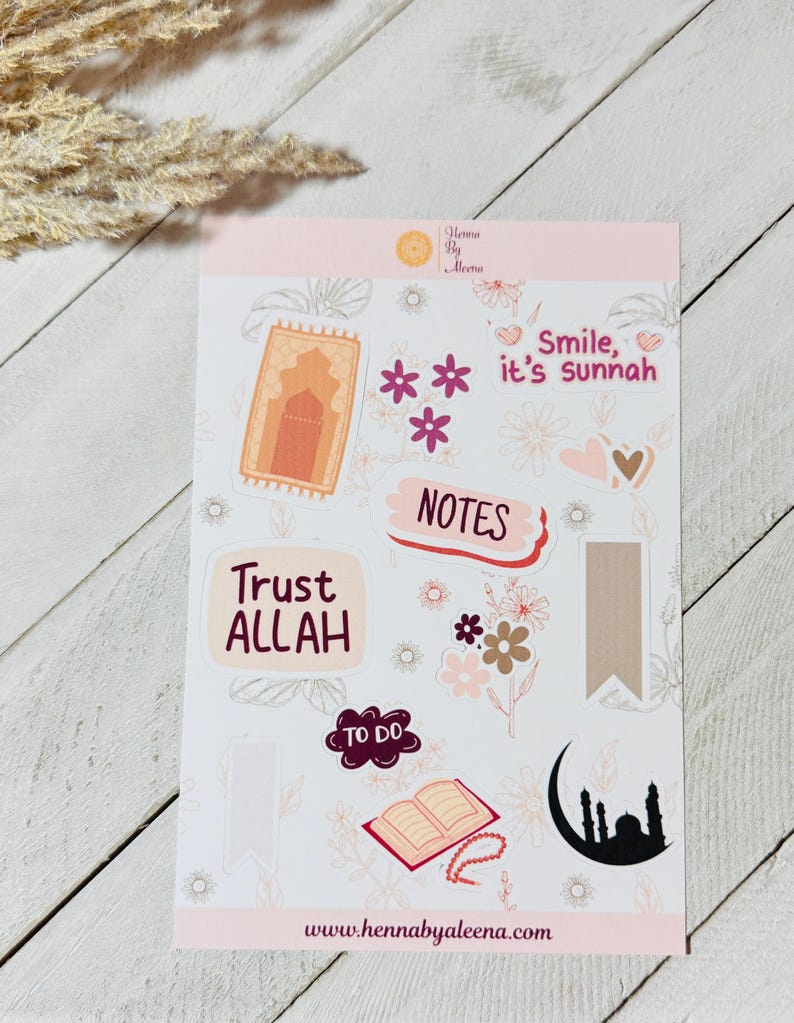 May include: A sticker sheet featuring Islamic-themed designs. The stickers include the phrases "Trust ALLAH" and "Smile, it's sunnah", alongside illustrations of a prayer rug, flowers, a mosque, and an open book. The website address "www.hennabyaleena.com" is also visible.