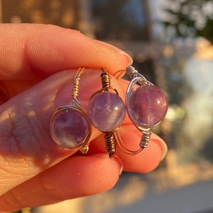 May include: Three gold wire wrapped rings with amethyst stones. The rings are stacked on top of each other.
