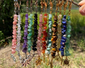 May include: A collection of ten beaded keychains featuring various polished gemstone chips in shades of pink, purple, green, black, red, orange, brown, yellow, and blue, each attached to a gold or silver metal lobster clasp and a charm.