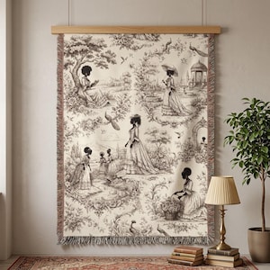 May include: A rectangular woven wall tapestry featuring a black and white toile de jouy pattern on a cream background. The design depicts various figures in period clothing within a landscape, framed by a wooden hanger and fringed edges.