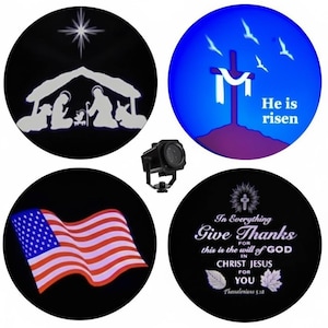 May include: A projector displaying four circular images. One shows a nativity scene, another a cross with "He is risen", a third the American flag, and the last reads "Give Thanks". The projector is black.