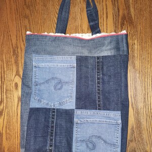 May include: A blue denim tote bag with four pockets, each with a decorative stitch. The bag has a white lace trim and a red accent.