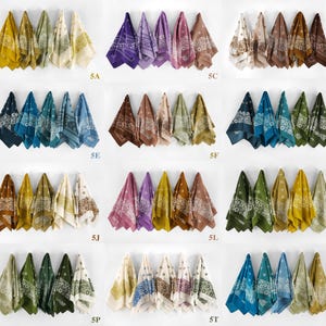 May include: A collection of bandanas in various colors, including yellow, purple, brown, and blue, each with a white floral paisley design. The bandanas are displayed in rows, showcasing the range of available colors and patterns.