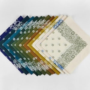 May include: A collection of square bandanas in various colors, arranged in a fan shape. The bandanas feature floral patterns and border designs. Colors include navy, teal, green, olive, gold, and cream. The bandanas are made of fabric.
