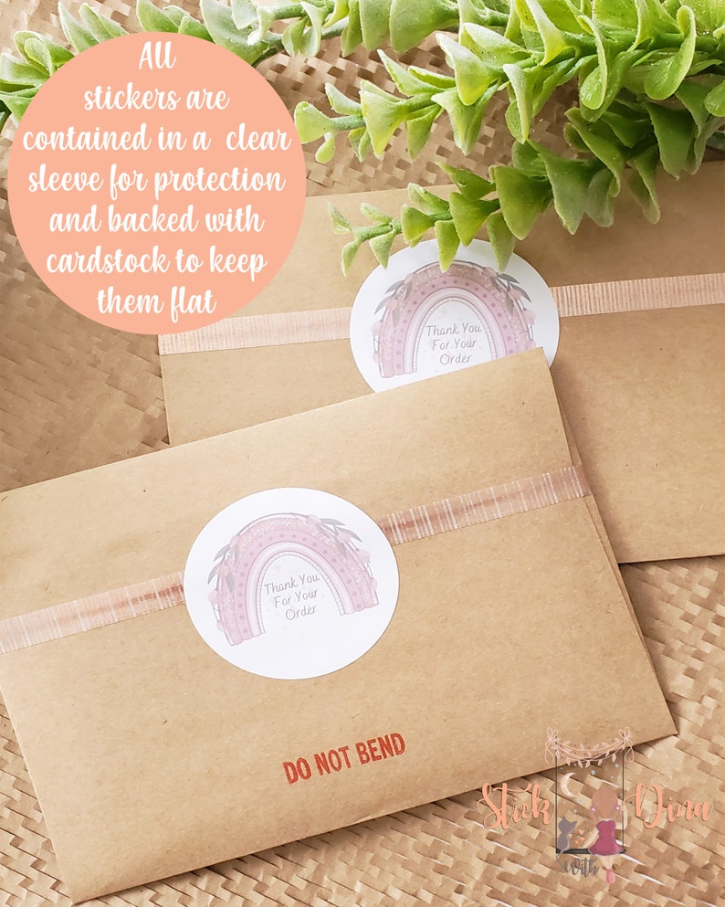 Peut inclure: Une enveloppe en papier kraft avec un autocollant "Merci pour votre commande" repr&eacute;sentant un arc-en-ciel avec des accents floraux. L'enveloppe porte une &eacute;tiquette rouge "NE PAS Plier" et est scell&eacute;e avec un ruban rose.