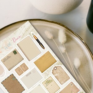 May include: A set of vintage-style printable stickers featuring various designs, including postcards, envelopes, tags, and a pen. The stickers are on a white background with a light brown map pattern.