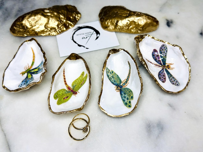 Handmade dragonfly oyster shell trinket dish with hand-gilded gold leaf edges and glossy resin finish, created from sustainably sourced Dorset shells. Unique coastal jewellery holder and ring dish, ideal as a vanity tray, trinket tray or decorative keepsake. Nature inspired home decor gift for birthdays, weddings, anniversaries, housewarmings and Mother’s Day. One of a kind artisan shell dish, beautifully presented in a gift box.