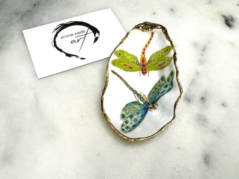 Handmade dragonfly oyster shell trinket dish with hand-gilded gold leaf edges and glossy resin finish, created from sustainably sourced Dorset shells. Unique coastal jewellery holder and ring dish, ideal as a vanity tray, trinket tray or decorative keepsake. Nature inspired home decor gift for birthdays, weddings, anniversaries, housewarmings and Mother’s Day. One of a kind artisan shell dish, beautifully presented in a gift box.