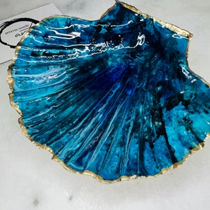 May include: A blue and white resin seashell with a gold rim. The seashell is a decorative object with a smooth, glossy finish.