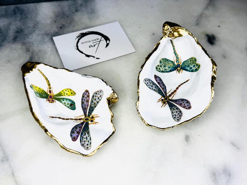 Handmade dragonfly oyster shell trinket dish with hand-gilded gold leaf edges and glossy resin finish, created from sustainably sourced Dorset shells. Unique coastal jewellery holder and ring dish, ideal as a vanity tray, trinket tray or decorative keepsake. Nature inspired home decor gift for birthdays, weddings, anniversaries, housewarmings and Mother’s Day. One of a kind artisan shell dish, beautifully presented in a gift box.