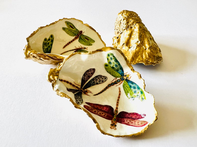 Handmade dragonfly oyster shell trinket dish with hand-gilded gold leaf edges and glossy resin finish, created from sustainably sourced Dorset shells. Unique coastal jewellery holder and ring dish, ideal as a vanity tray, trinket tray or decorative keepsake. Nature inspired home decor gift for birthdays, weddings, anniversaries, housewarmings and Mother’s Day. One of a kind artisan shell dish, beautifully presented in a gift box.