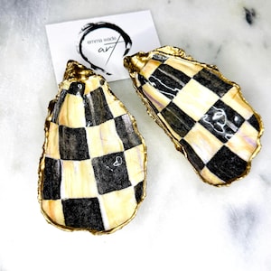 May include: Two oyster shell dishes with a black and white chequered pattern. The shells are gold-gilded and have a glossy finish.