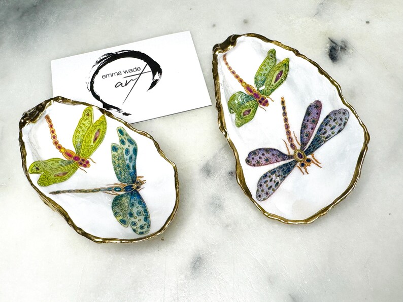 Handmade dragonfly oyster shell trinket dish with hand-gilded gold leaf edges and glossy resin finish, created from sustainably sourced Dorset shells. Unique coastal jewellery holder and ring dish, ideal as a vanity tray, trinket tray or decorative keepsake. Nature inspired home decor gift for birthdays, weddings, anniversaries, housewarmings and Mother’s Day. One of a kind artisan shell dish, beautifully presented in a gift box.