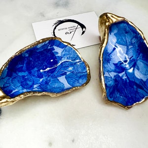 May include: Two blue and white oyster shell dishes with gold trim. The shells are painted with a floral design.