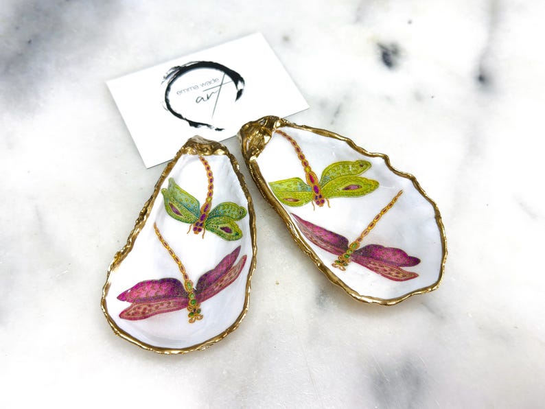 Handmade dragonfly oyster shell trinket dish with hand-gilded gold leaf edges and glossy resin finish, created from sustainably sourced Dorset shells. Unique coastal jewellery holder and ring dish, ideal as a vanity tray, trinket tray or decorative keepsake. Nature inspired home decor gift for birthdays, weddings, anniversaries, housewarmings and Mother’s Day. One of a kind artisan shell dish, beautifully presented in a gift box.