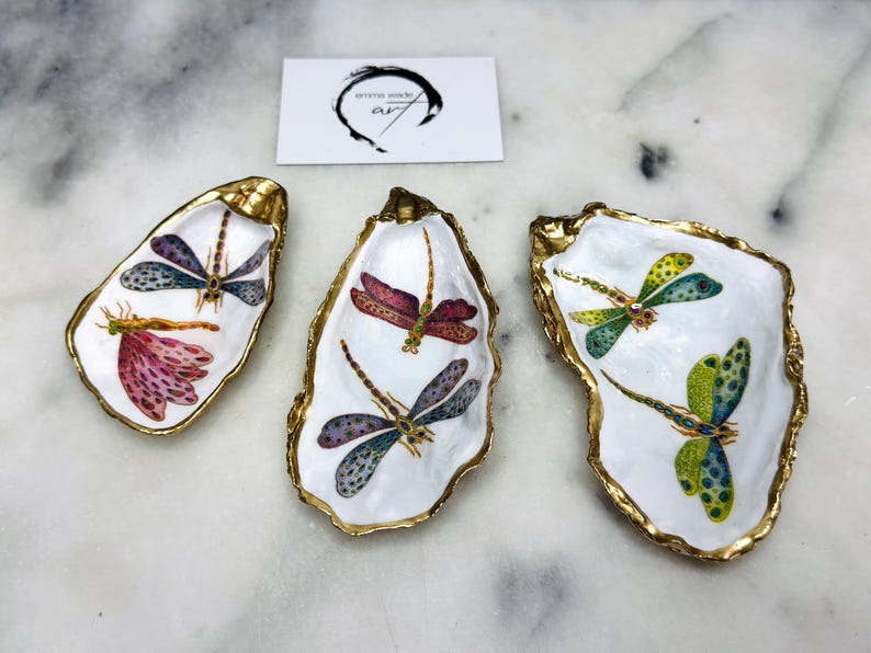 Handmade dragonfly oyster shell trinket dish with hand-gilded gold leaf edges and glossy resin finish, created from sustainably sourced Dorset shells. Unique coastal jewellery holder and ring dish, ideal as a vanity tray, trinket tray or decorative keepsake. Nature inspired home decor gift for birthdays, weddings, anniversaries, housewarmings and Mother’s Day. One of a kind artisan shell dish, beautifully presented in a gift box.