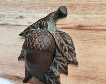 Aldaba de puerta de latón macizo con forma de bellota y acabado pátina verdosa.