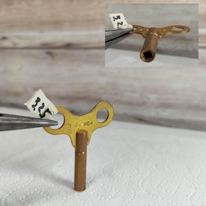 May include: A gold-colored metal clock key with a T-shaped handle and a square end. The key is labeled "3-25-NO.4".