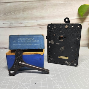 May include: An antique Meccano No. 1 Clockwork Motor set with a key and a black metal component. The blue box has the text "MECCANO" and "No. 1 CLOCKWORK MOTOR". The key is dark brown and the metal component is rectangular.