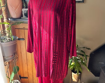 May include: A long-sleeved red dress with a black and red striped pattern. The dress has a round neckline and a slightly flared skirt. The dress is on a mannequin.