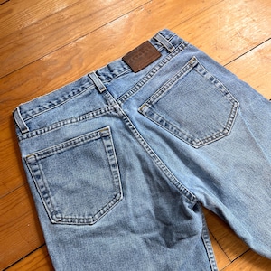May include: A pair of light blue denim jeans with a brown leather patch on the back that says "NEVADA" in white lettering.