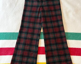 May include: High-waisted plaid pants in a classic tartan pattern. The pants feature a red, green, and black color scheme. The wide-leg design is visible in this full shot of the garment.