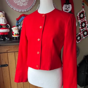 May include: A bright red cropped blazer with long sleeves and button fastenings. The blazer is on a white mannequin.