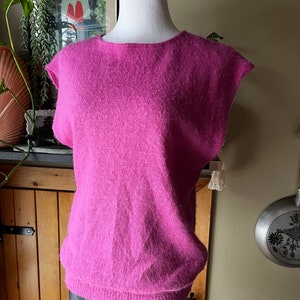 May include: A fluffy pink sleeveless sweater with a round neckline. The sweater is made of a soft, fluffy material.