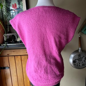 May include: A pink fluffy sleeveless sweater with a scoop neck.