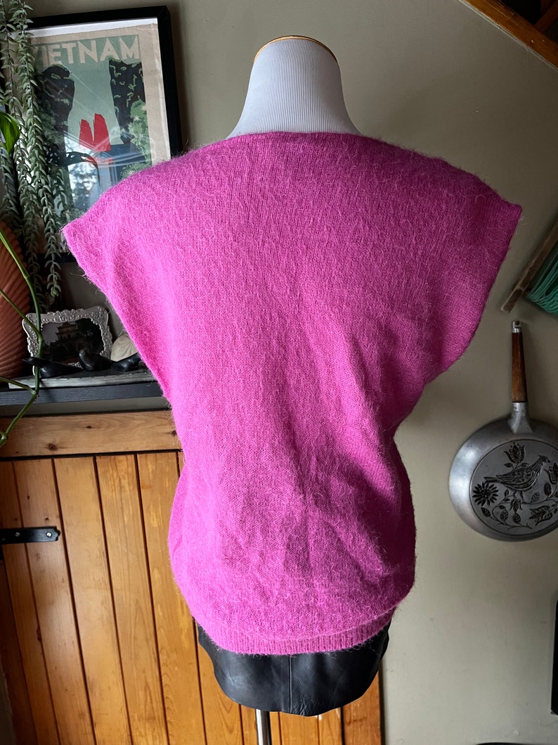 May include: A pink fluffy sleeveless sweater with a scoop neck.
