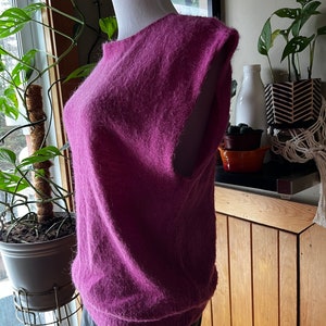 May include: A fluffy, sleeveless sweater in a deep purple colour. The sweater is made of a soft, fluffy material and has a relaxed fit.