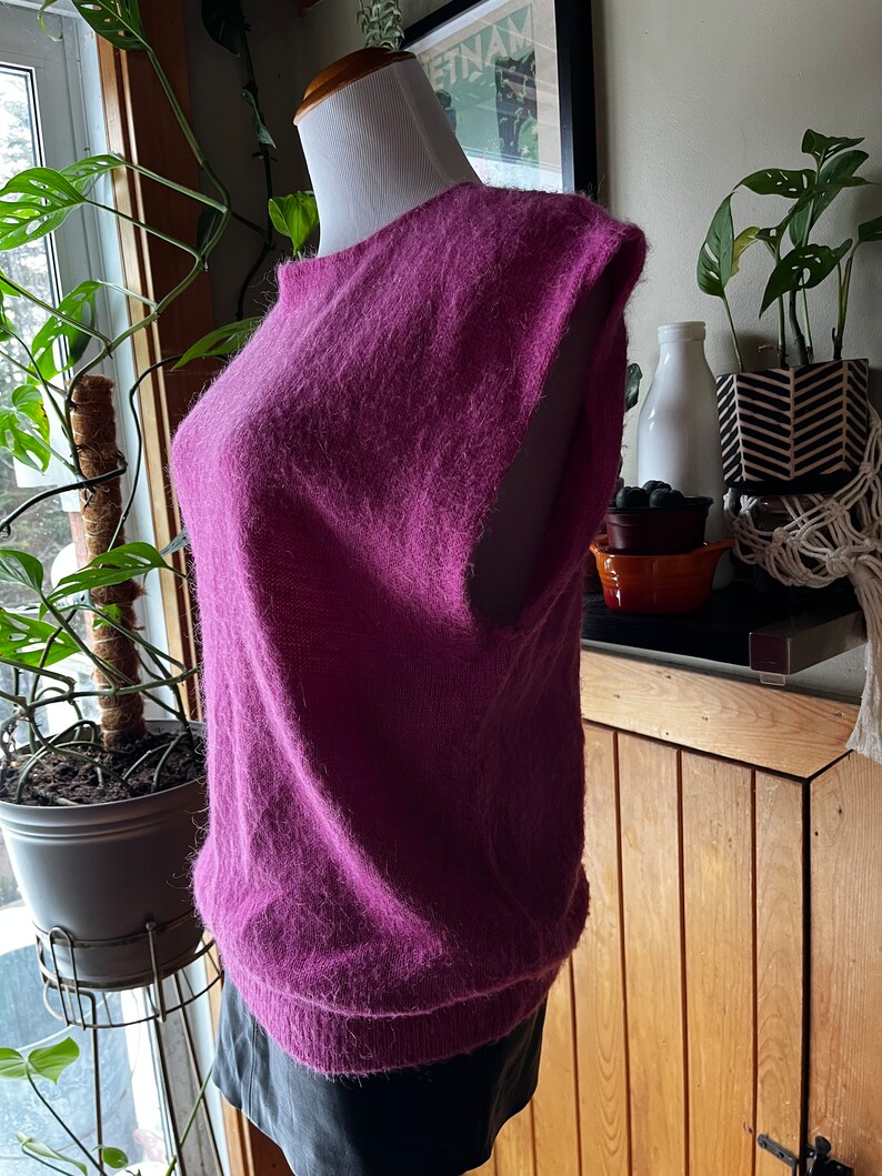 May include: A fluffy, sleeveless sweater in a deep purple colour. The sweater is made of a soft, fluffy material and has a relaxed fit.