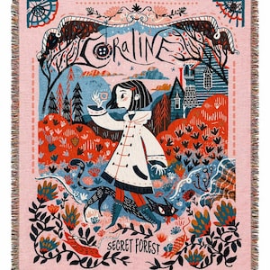 Puede incluir: Manta tejida rosa con una ilustraci&oacute;n detallada. La palabra "CORALINE" est&aacute; en la parte superior, con una ni&ntilde;a con abrigo blanco y un gato negro en una escena de bosque. Las palabras "SECRET FOREST" est&aacute;n en la parte inferior.