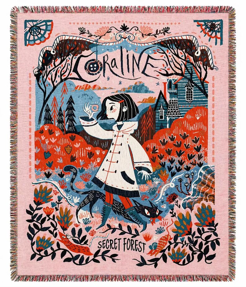 Puede incluir: Manta tejida rosa con una ilustraci&oacute;n detallada. La palabra "CORALINE" est&aacute; en la parte superior, con una ni&ntilde;a con abrigo blanco y un gato negro en una escena de bosque. Las palabras "SECRET FOREST" est&aacute;n en la parte inferior.