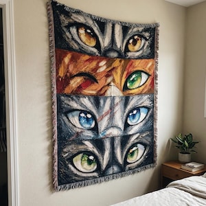 May include: A woven wall tapestry depicting four pairs of cat eyes in shades of gold, orange, blue, and green. The artwork has a textured finish and is bordered with a fringed edge. The tapestry is displayed on a neutral-toned wall.