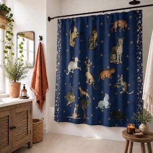 May include: A dark blue shower curtain featuring a repeating pattern of various cats in different poses, including one wearing a crown, interspersed with small gold star icons. The curtain has a vertical floral border on the left and right sides.