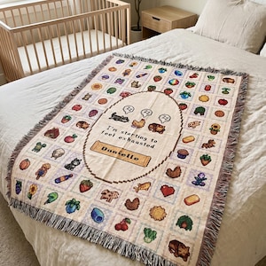 Op de afbeelding: Een beige sprei met een gepixeld ontwerp met verschillende illustraties van voedsel en dieren. De sprei heeft een centraal ovaal met de tekst "I'm starting to feel exhausted. Danielle". De sprei heeft een gefranjerde rand en wordt op een bed getoond.