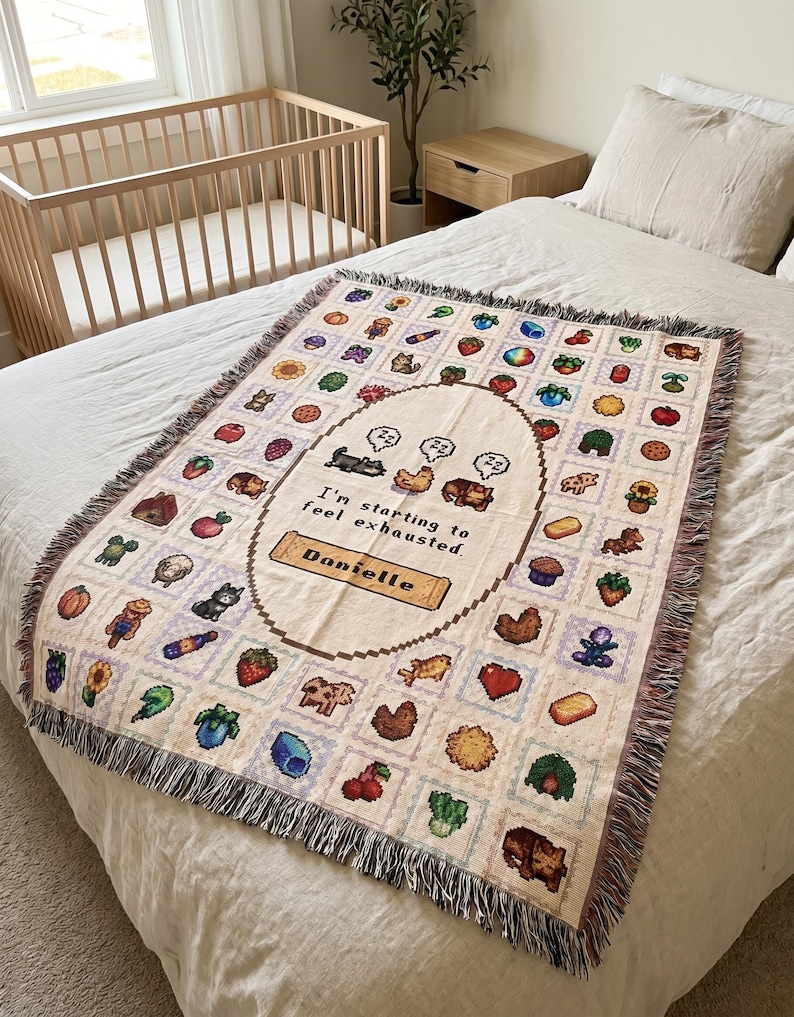 Op de afbeelding: Een beige sprei met een gepixeld ontwerp met verschillende illustraties van voedsel en dieren. De sprei heeft een centraal ovaal met de tekst "I'm starting to feel exhausted. Danielle". De sprei heeft een gefranjerde rand en wordt op een bed getoond.