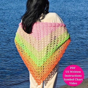 May include: A rainbow crochet shawl with a pink, green, orange, and yellow color gradient. The shawl is draped over a person's shoulders. The image includes the text "PDF US Written Instructions Symbol Chart Video".