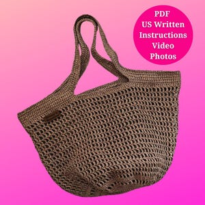 May include: A crocheted tote bag in a neutral brown color, featuring a mesh-like design. The bag has two handles and a small rectangular tag. A pink circle in the background contains the text "PDF US Written Instructions Video Photos".