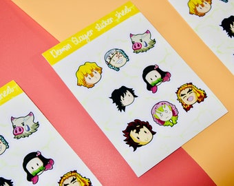 May include: A sheet of Demon Slayer character stickers featuring various characters from the anime series. The stickers are printed on white paper with a yellow background and feature characters such as Tanjiro, Nezuko, Zenitsu, Inosuke, and Giyu.