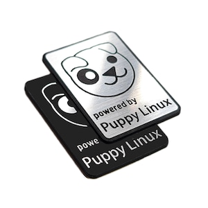以下が含まれることがあります： スタイライズされた子犬の顔のグラフィックと「powered by Puppy Linux」というテキストが描かれた2枚の長方形の金属製ステッカー。1枚はつや消しシルバー仕上げに黒のテキスト、もう1枚はマットブラックにシルバーのテキストとグラフィックが施されています。