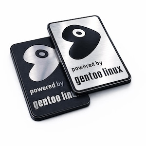 May include: Two rectangular metal badges with rounded corners. One badge has a brushed silver finish with a black logo and the text "powered by gentoo linux". The other badge has a black finish with a silver logo and the text "powered by gentoo linux".