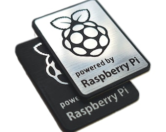 May include: Two Raspberry Pi stickers, one silver and one black, with the Raspberry Pi logo and the text "powered by Raspberry Pi".